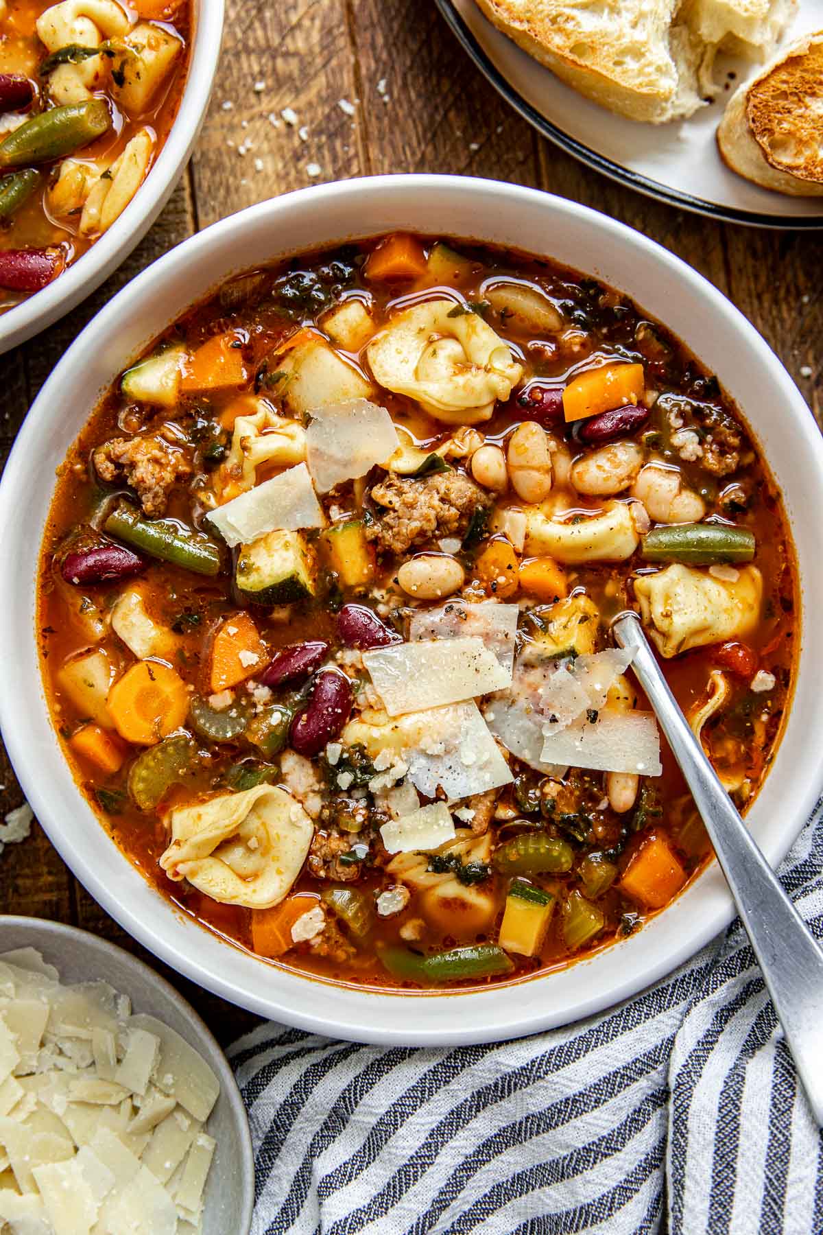 a bowl of minestrone in a large bowl with parmesan on top. 