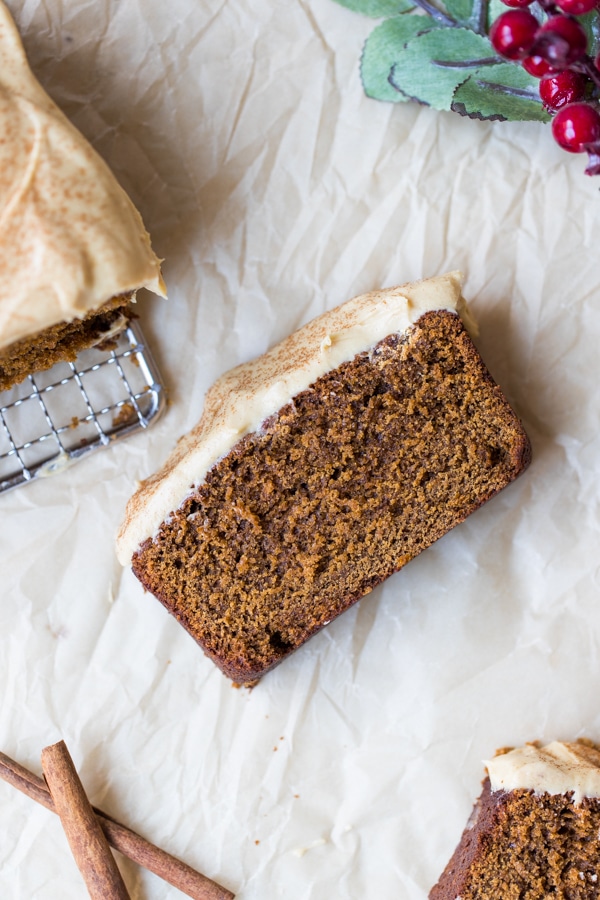 a slice of gingerbread on parchment paper with cream cheese frosting on top