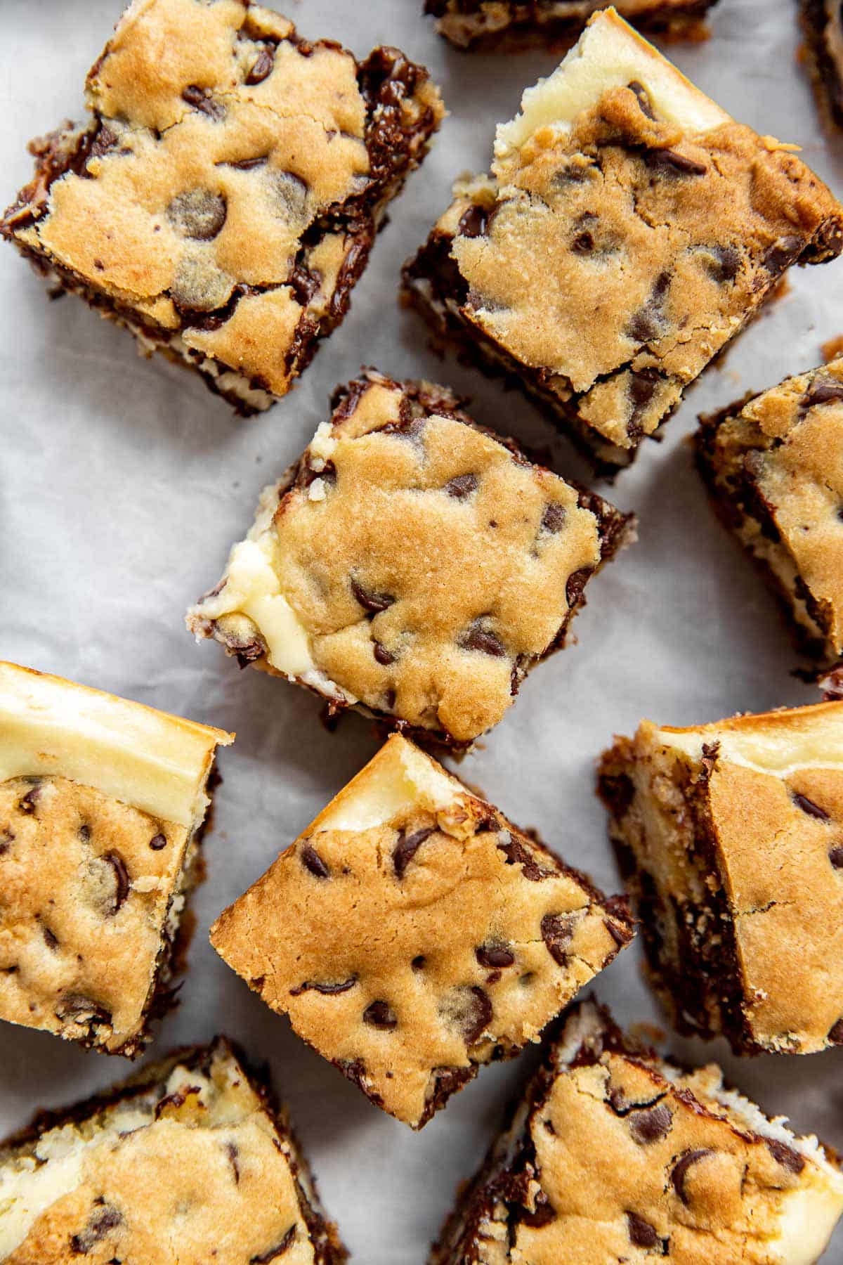 Cheesecake cookie bars cut into squares on parchment paper. 