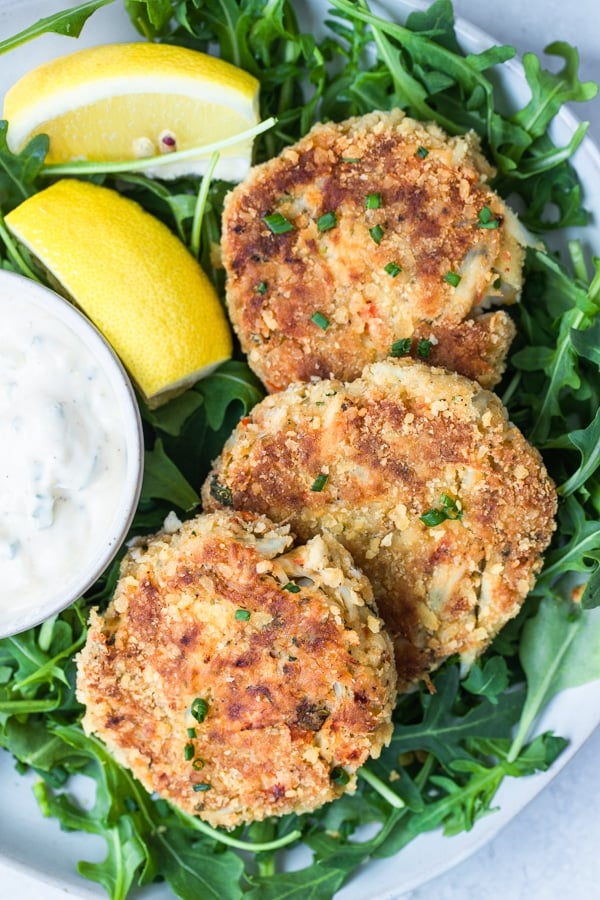 crab cakes on a white plate with arugula