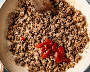Adding ketchup and Worcestershire sauce to ground beef.