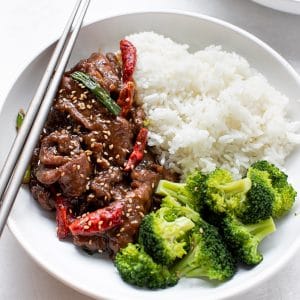 Mongolian beef with rice and broccoli in a white bowl