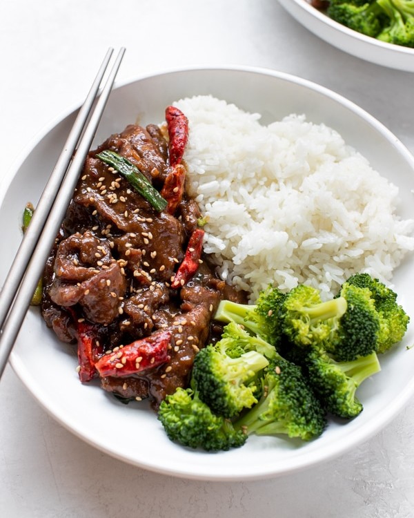 Mongolian beef with rice and broccoli in a white bowl