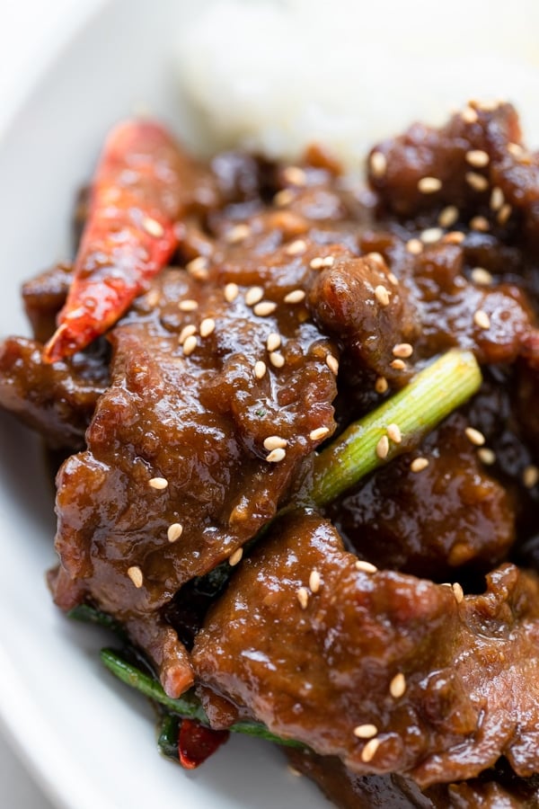 a close up image of Mongolian beef garnished with sesame seeds