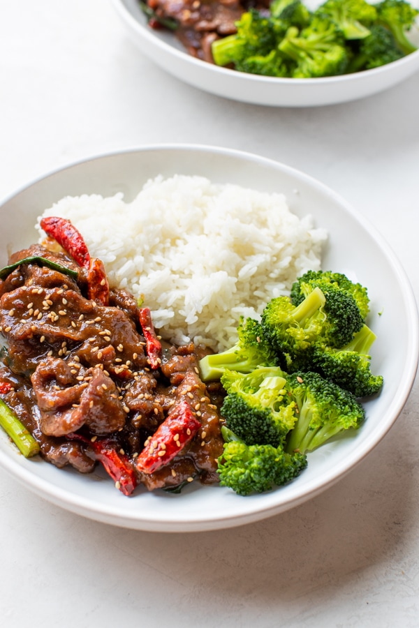 Mongolian Beef in a white bowl with rice and broccoli 