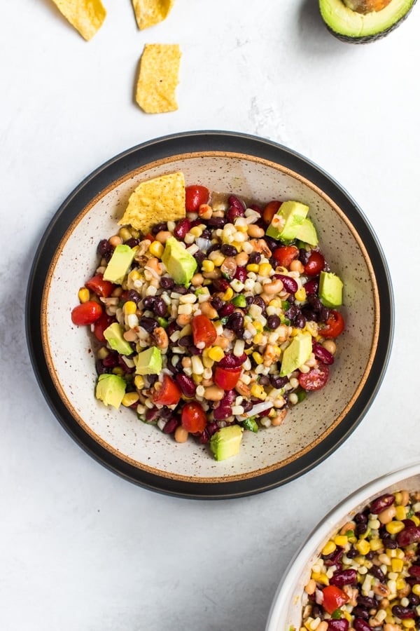 texas caviar topped with avocado in a cream colored bowl