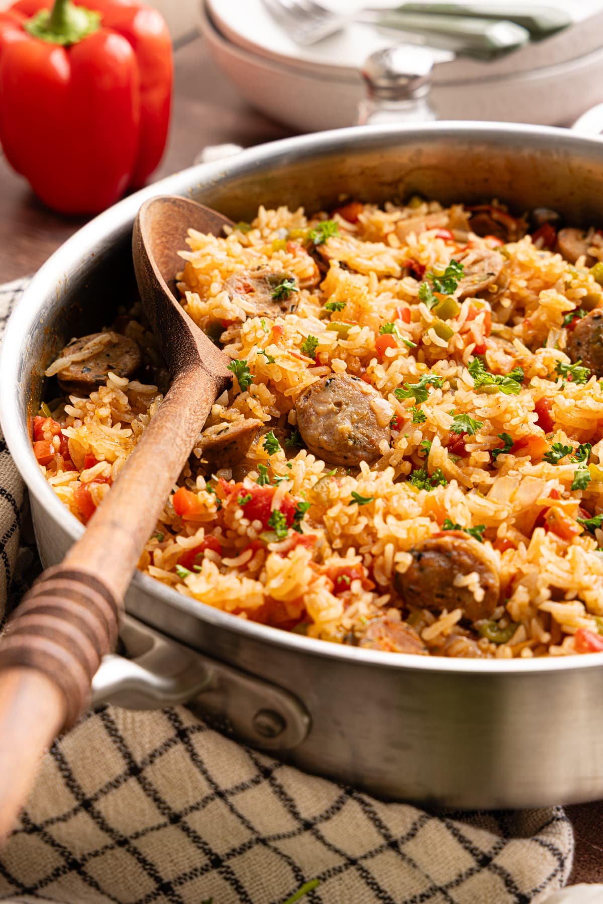 Close-up of sausage, peppers, and rice skillet with fluffy rice, sliced chicken sausage, and diced bell peppers in a stainless steel pan.