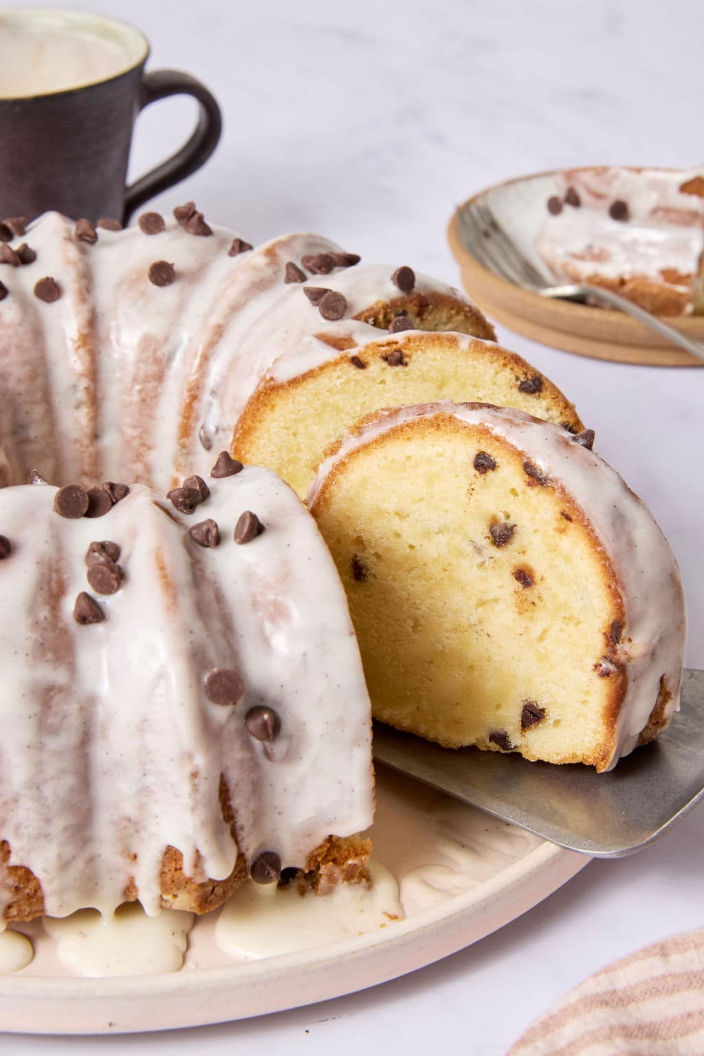 Several slices of chocolate chip Bundt cake arranged slightly apart, showcasing the soft vanilla cake crumb filled with mini chocolate chips and covered with vanilla bean glaze.