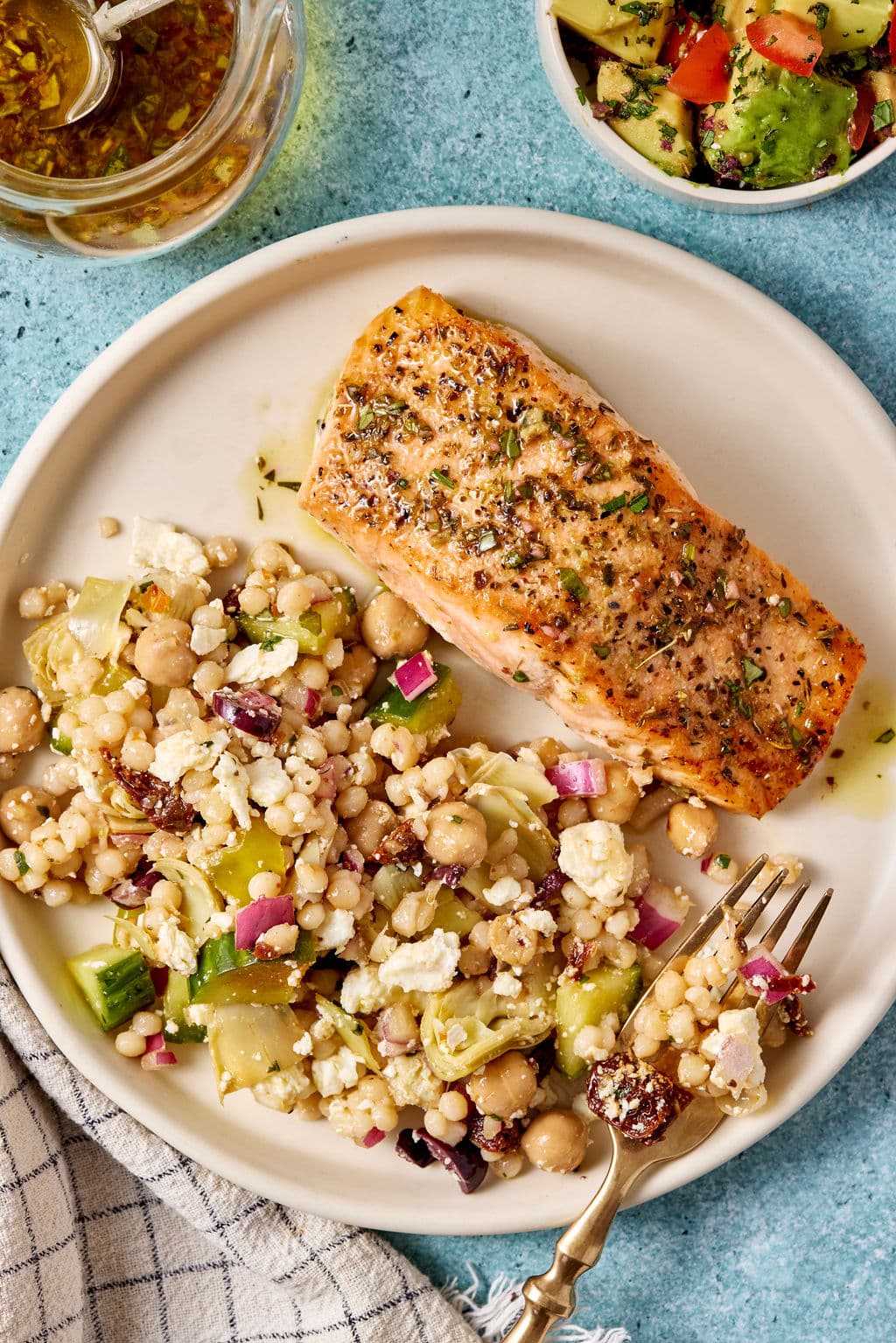 Pan-seared Mediterranean salmon served with pearl couscous salad made with chickpeas, cucumber, artichokes, feta, and sun-dried tomatoes.