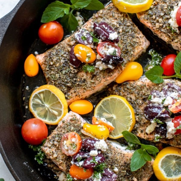 salmon in a cast iron skillet with tomatoes and kalamata olives
