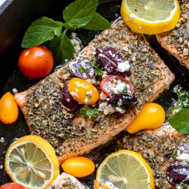 salmon in a cast iron skillet with tomatoes and kalamata olives