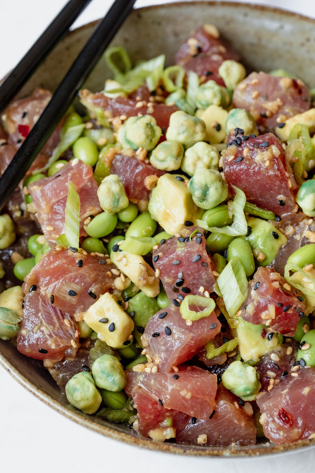 ahi poke in a brown bowl topped with green onions