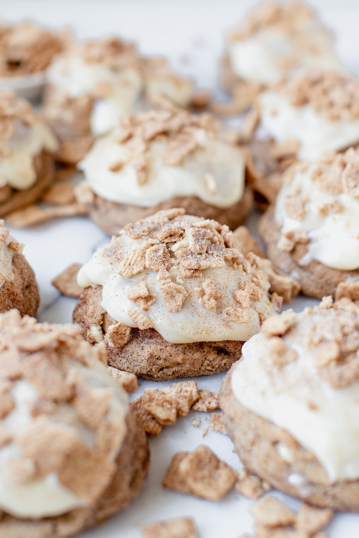 cinnamon toast crunch cookies on a marble slab coated in cream cheese frosting