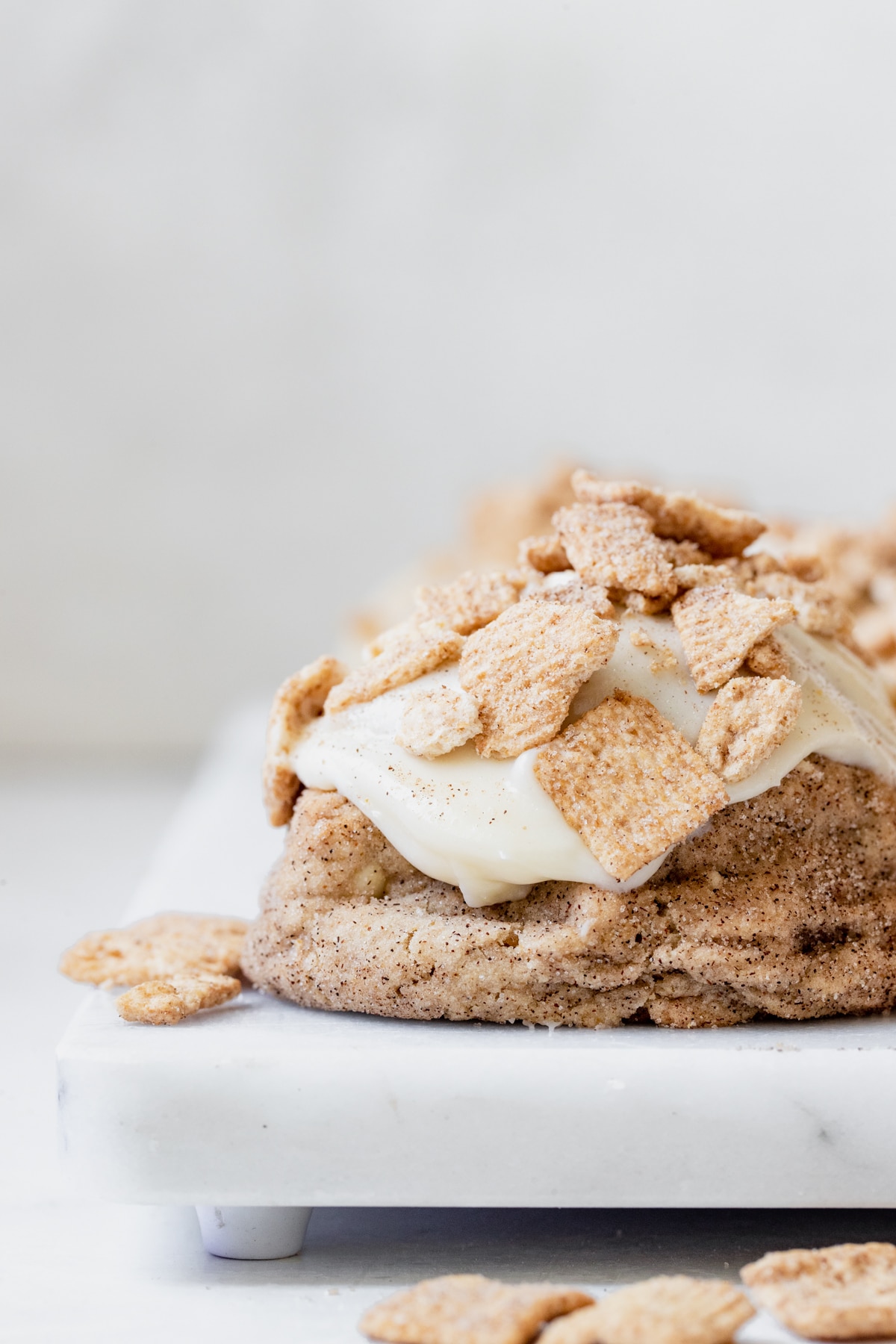 cinnamon toast crunch cookie on a marble slab coated in cream cheese frosting