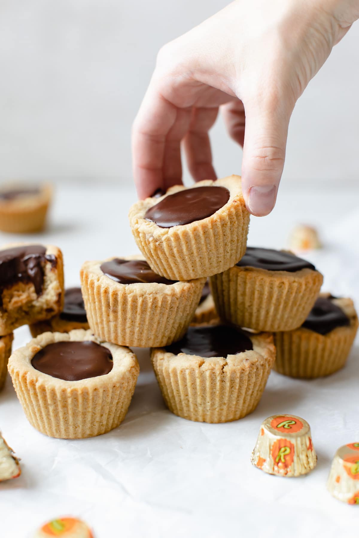 a woman's hand picking up a peanut butter cup cookie