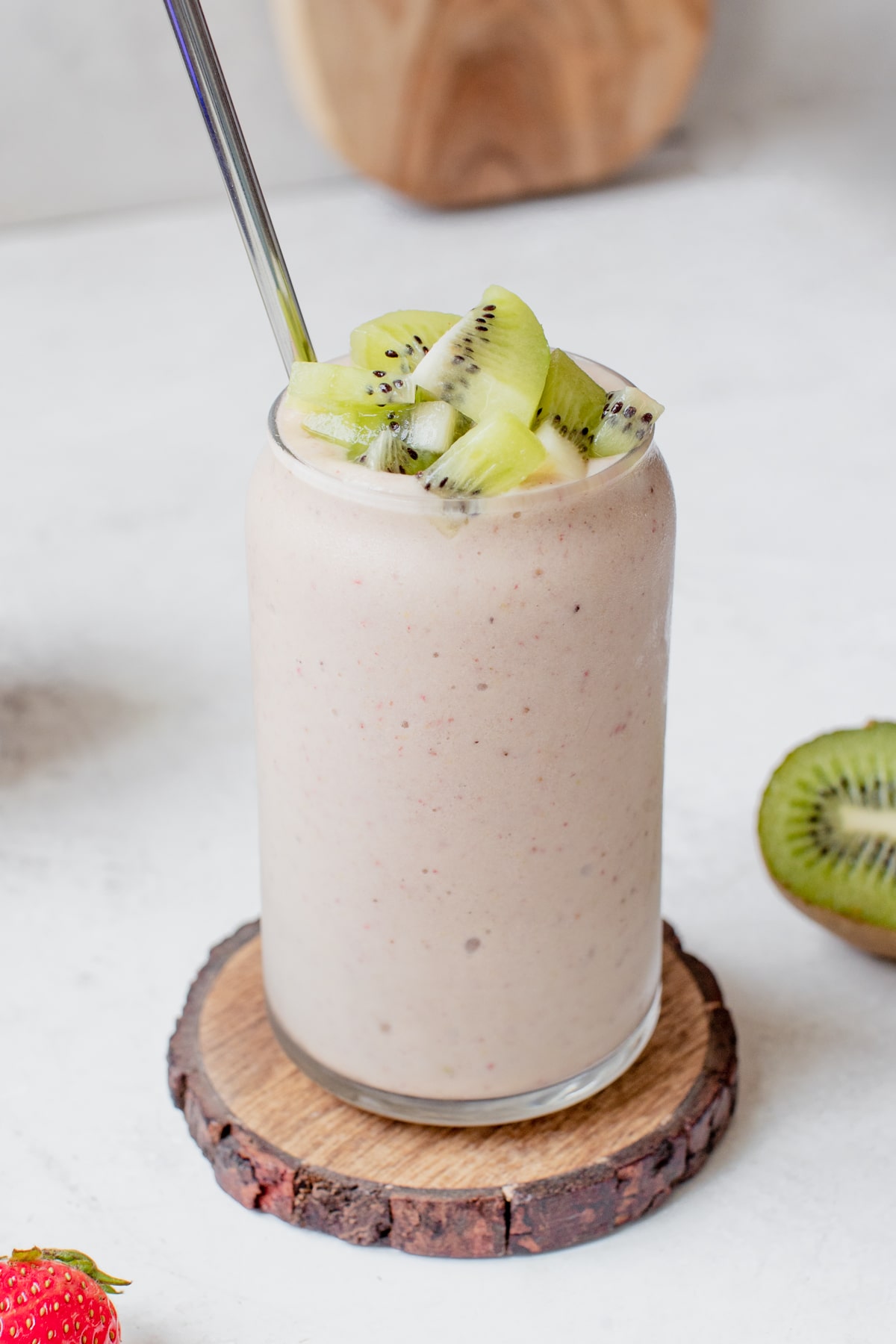 strawberry kiwi smoothie in a glass topped with diced fresh kiwi chunks