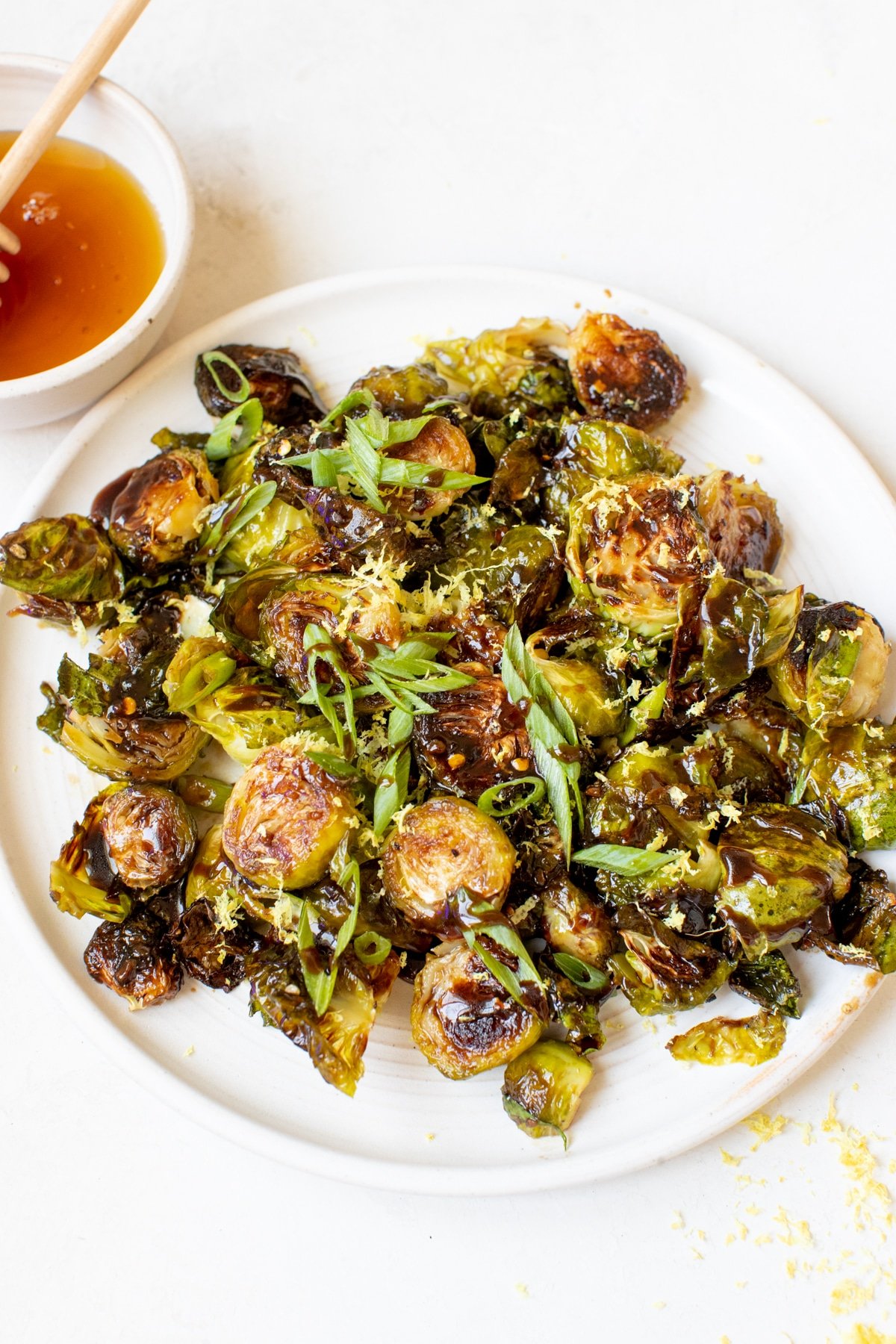 roasted brussels sprouts on a white plate garnished with green onions and lemon zest