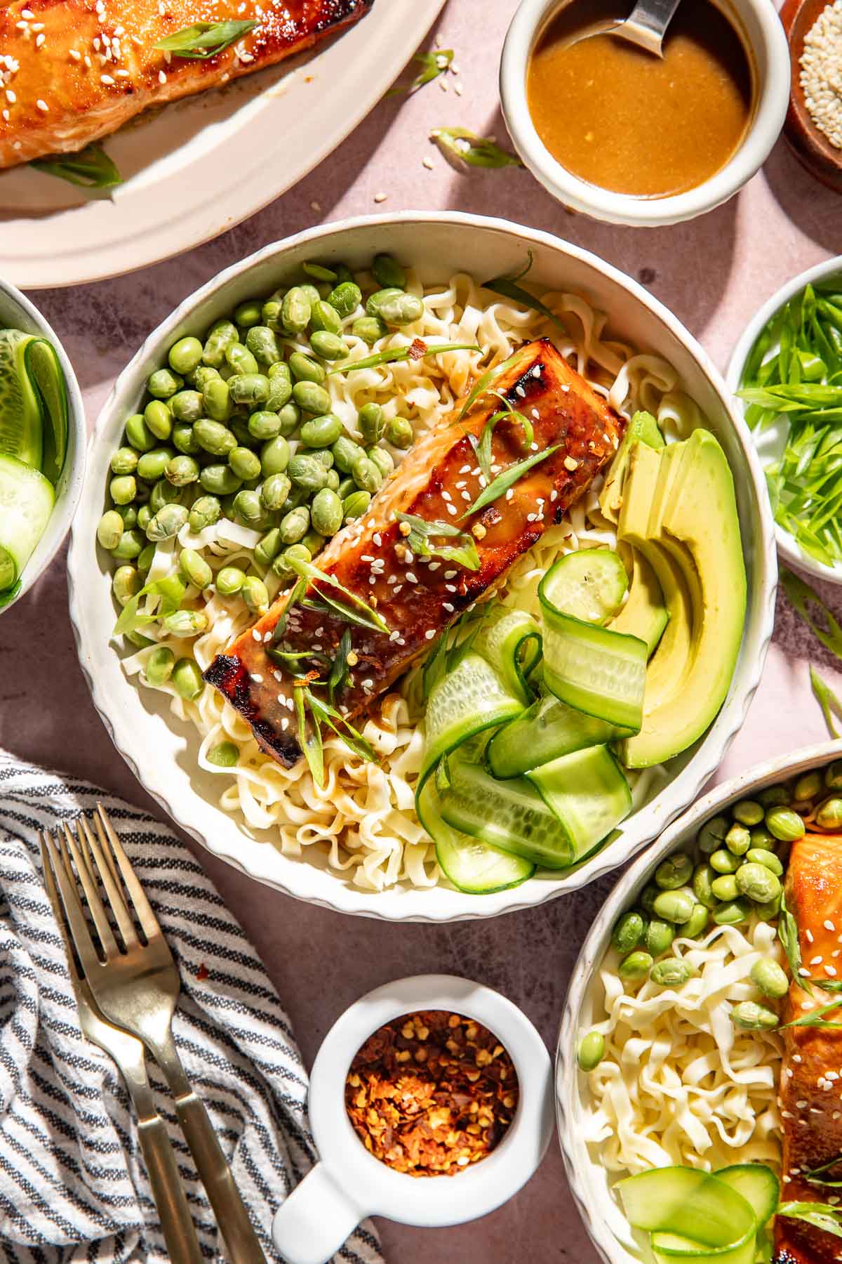 Brown sugar miso glazed salmon noodle bowl with ramen noodles, edamame, avocado, cucumber ribbons, sesame seeds, and sliced green onions.