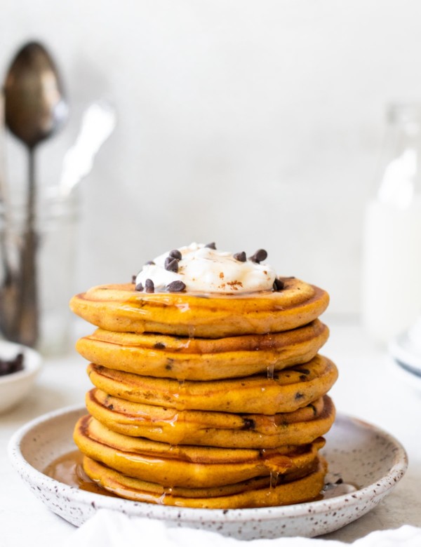 a stack of pancakes on a white specked plate