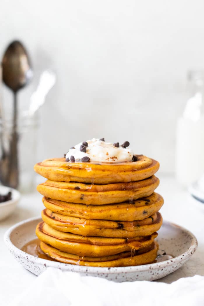 a stack of pancakes on a white specked plate