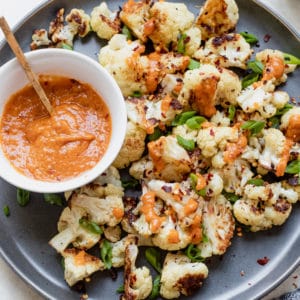 roasted cauliflower on a dark grey plate with miso sauce and green onions on top