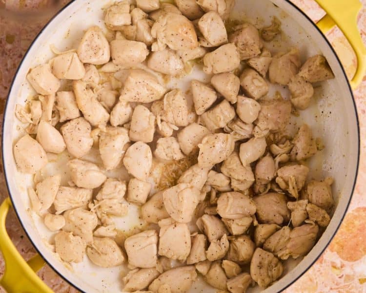 Dutch oven pot with cubed chicken breast seasoned with salt and pepper and fully cooked.