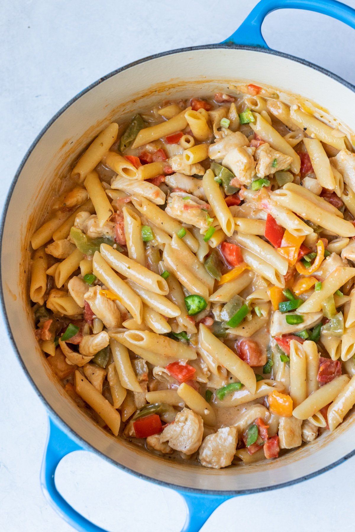 a photo of penne pasta with chicken, bell peppers and jalapeno in a blue dutch oven pot 