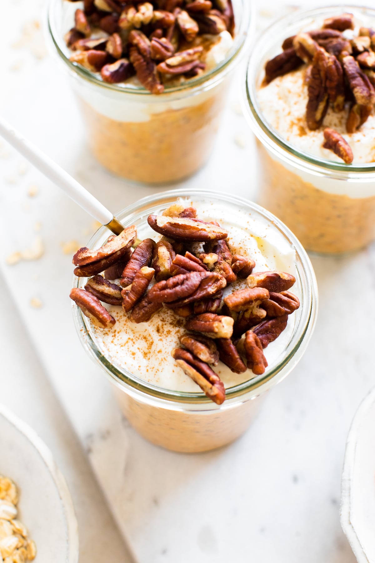 overnight oatmeal made with pumpkin in a class jar topped with Greek yogurt, chopped pecans and cinnamon 