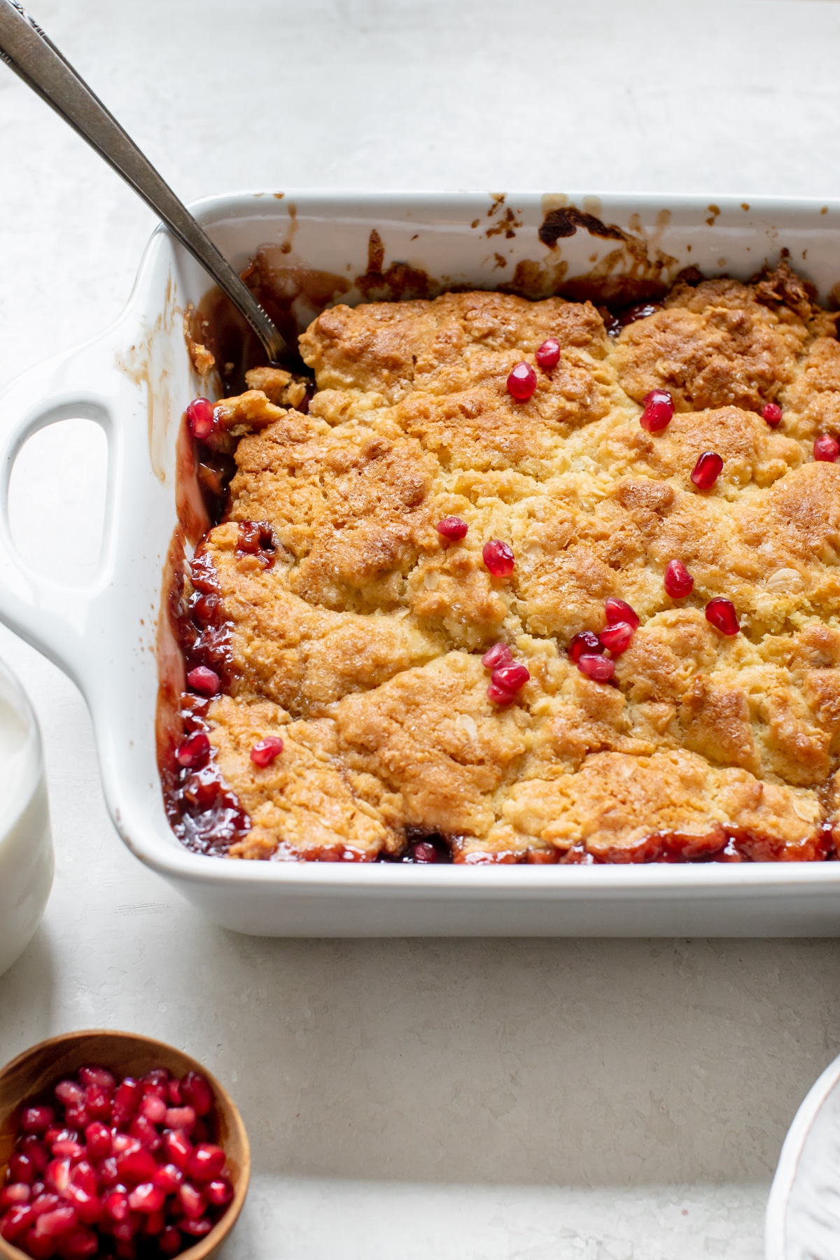 cobbler in a white baking dish topped with pomegranate seeds