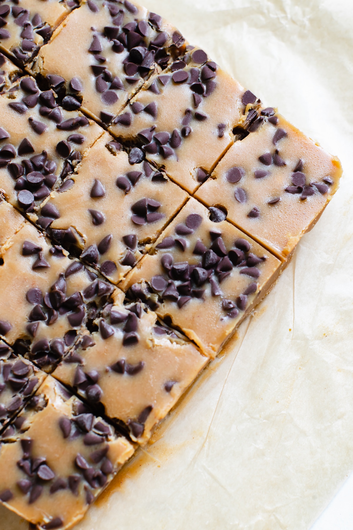pumpkin candy fudge on parchment paper coated in mini chocolate chips cut into small squares