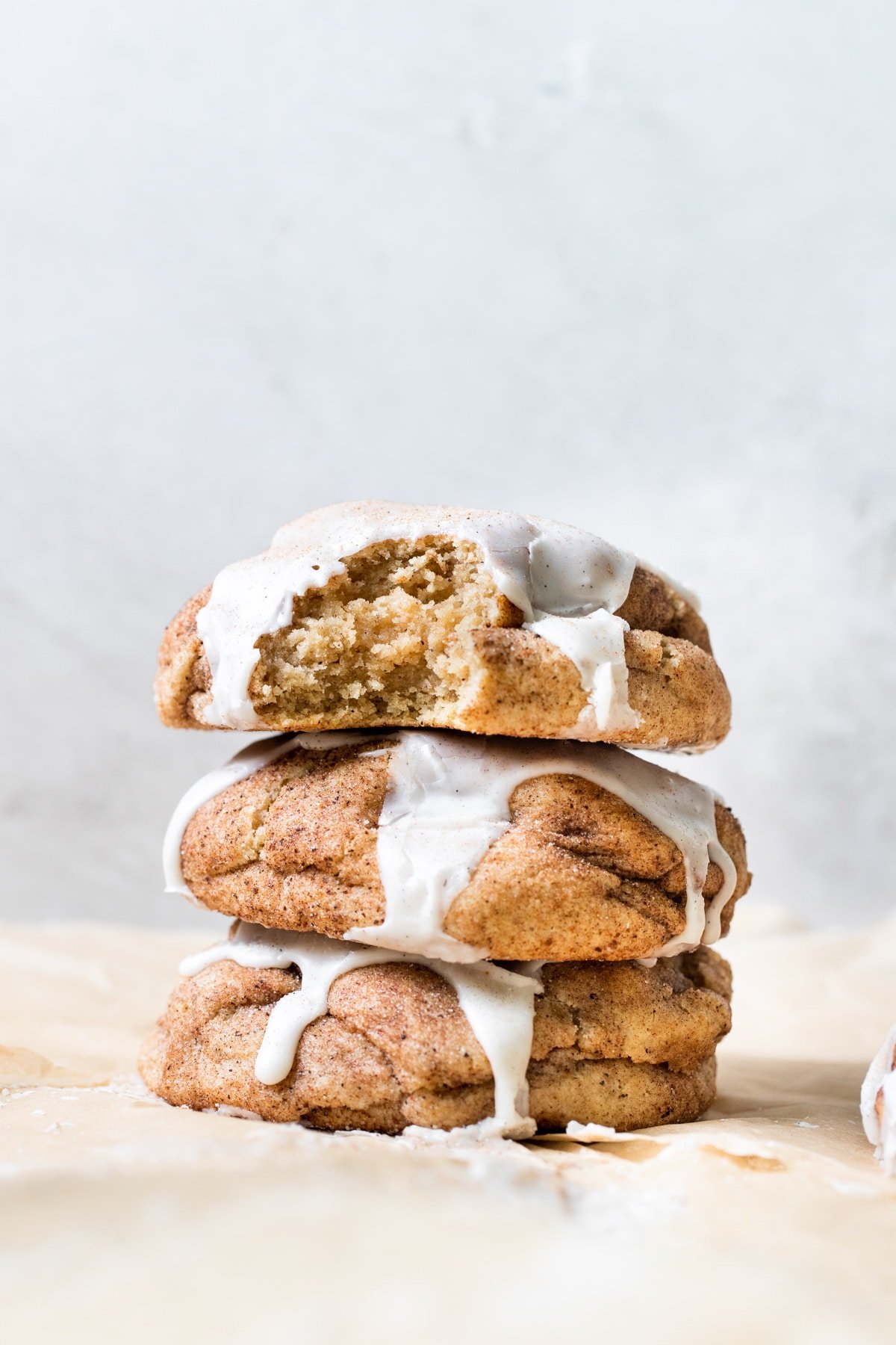 a stack of cookies on parchment paper topped with vanilla bean glaze