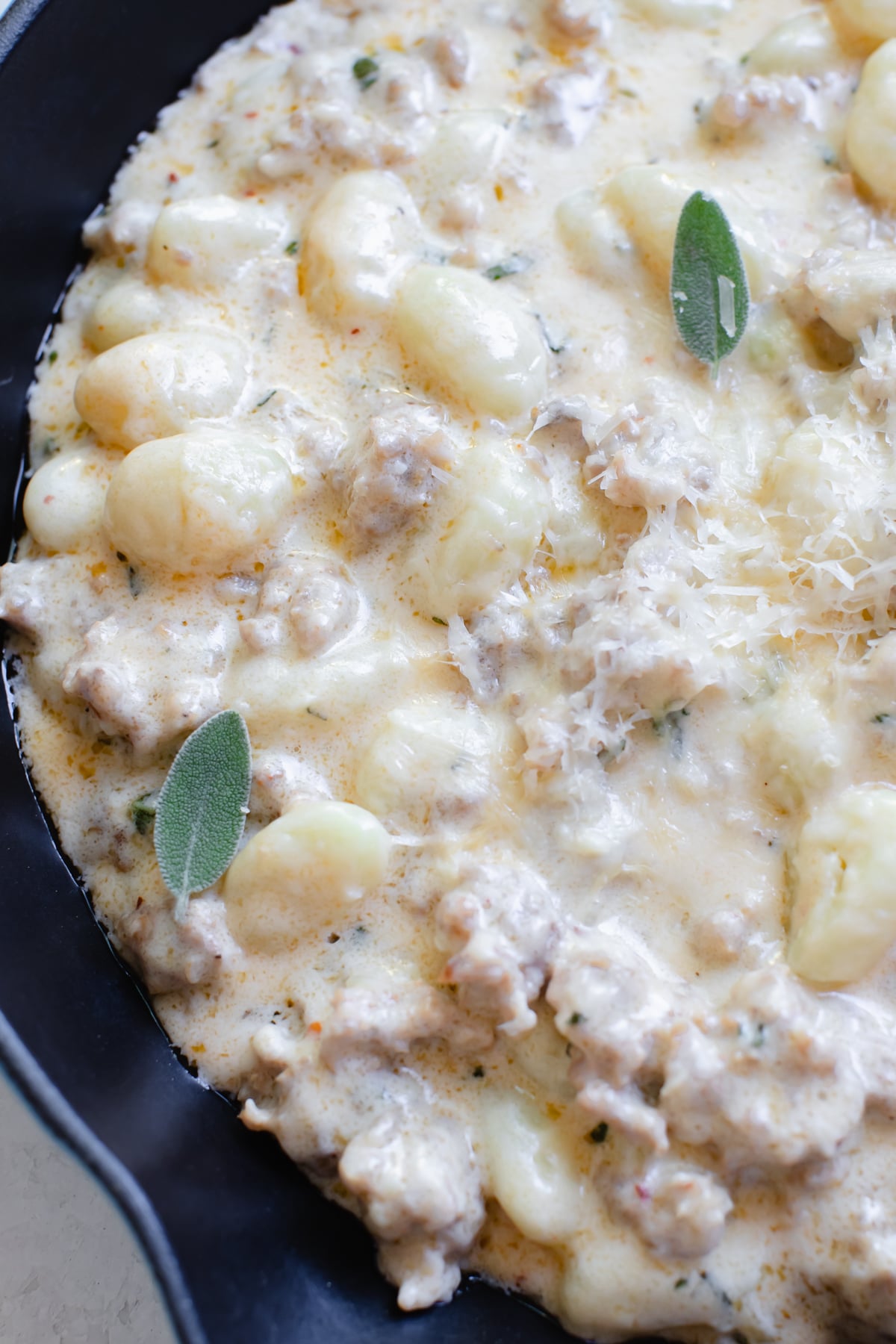 gnocchi and Italian sausage in a cast iron skillet topped with parmesan cheese