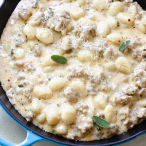 gnocchi and Italian sausage in a cast iron skillet topped with parmesan cheese