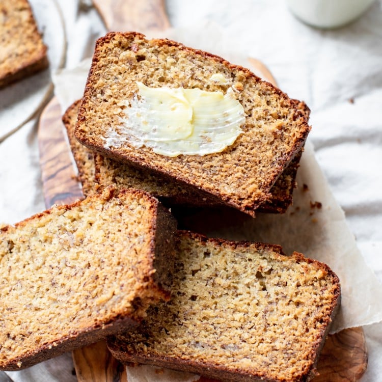 banana bread on a cutting board with butter smeared on top of one slice