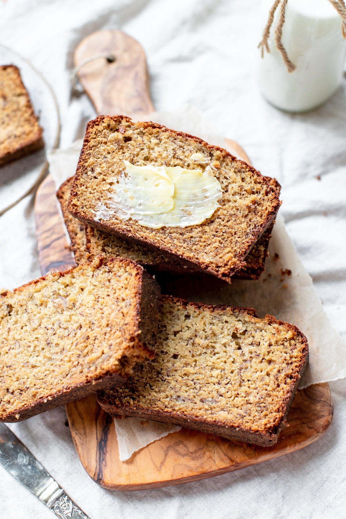 banana bread on a cutting board with butter smeared on top of one slice