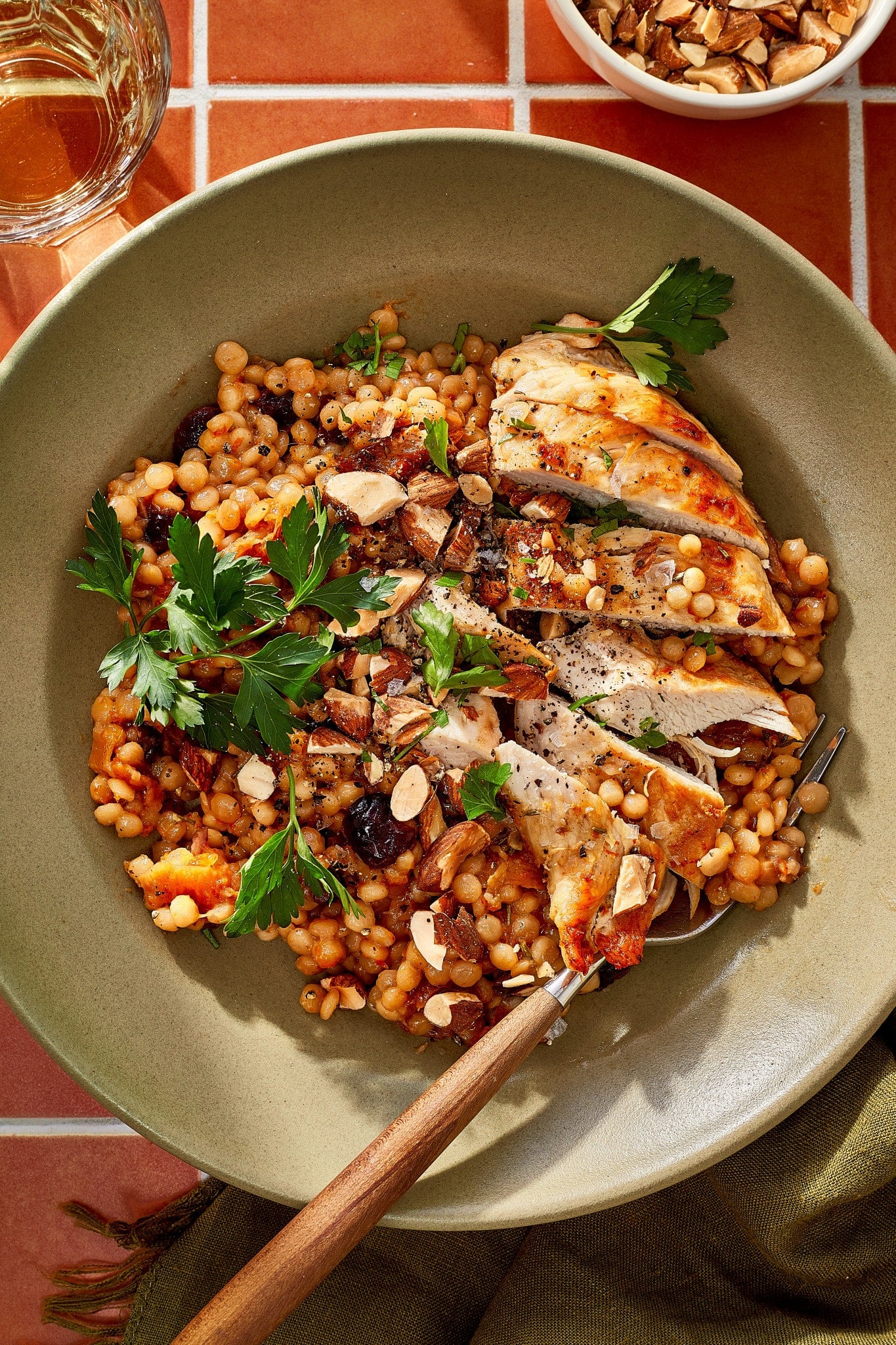 Sliced cranberry apricot chicken served over pearl couscous with dried cranberries, apricots, chopped almonds, and fresh parsley.