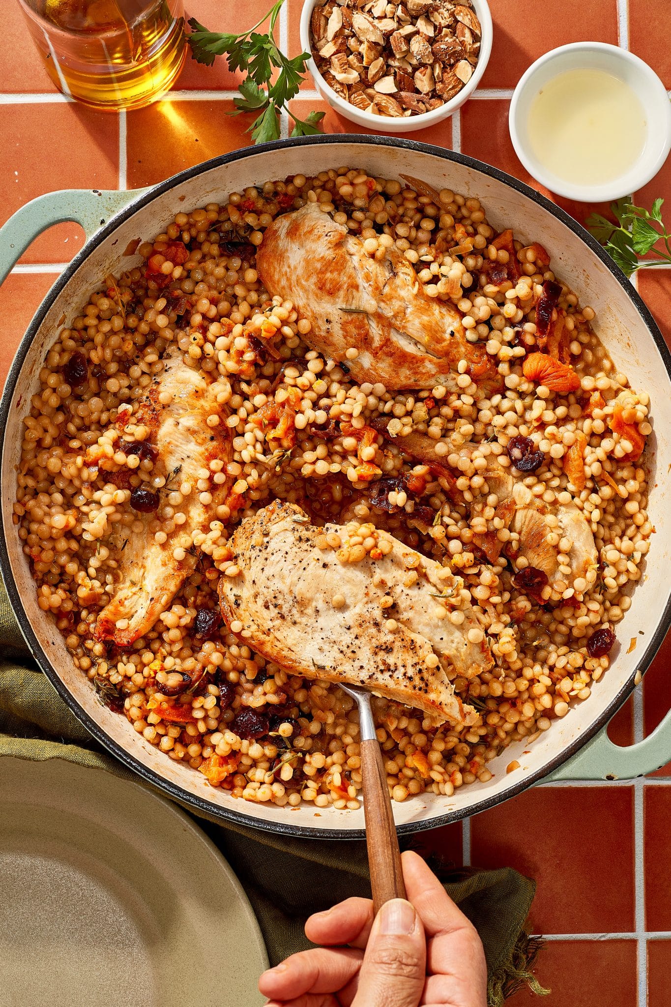 One-pan cranberry apricot chicken with pearl couscous, dried cranberries, apricots, and herbs in a large skillet.
