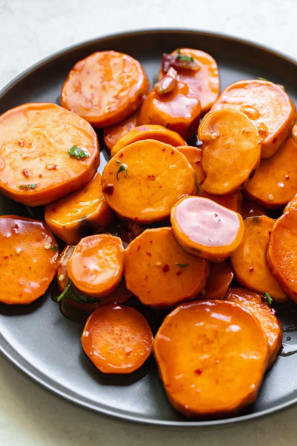 sweet potatoes covered in a honey glaze on a dark blue plate