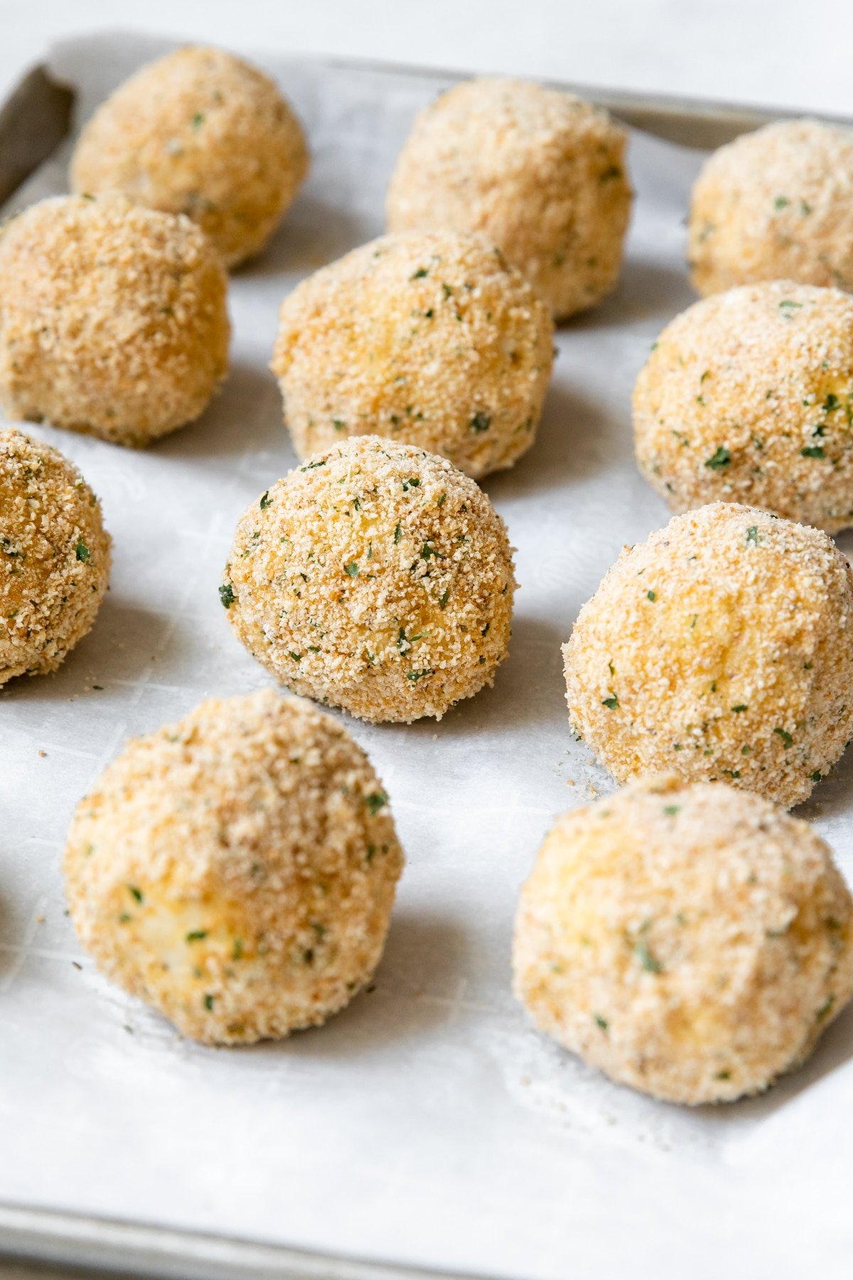 rice balls rolled in breadcrumbs on parchment paper