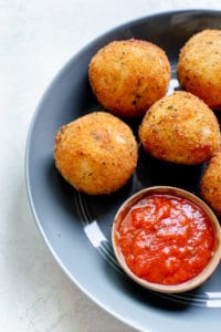 fried rice formed into balls on a blue plate with marinara