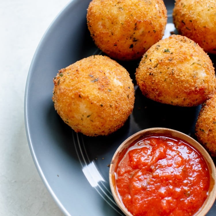 fried rice formed into balls on a blue plate with marinara