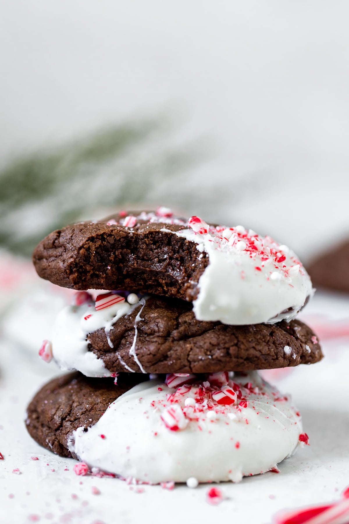 a stack of chocolate cookies dipped in white chocolate and garnished with crushed candy canes 
