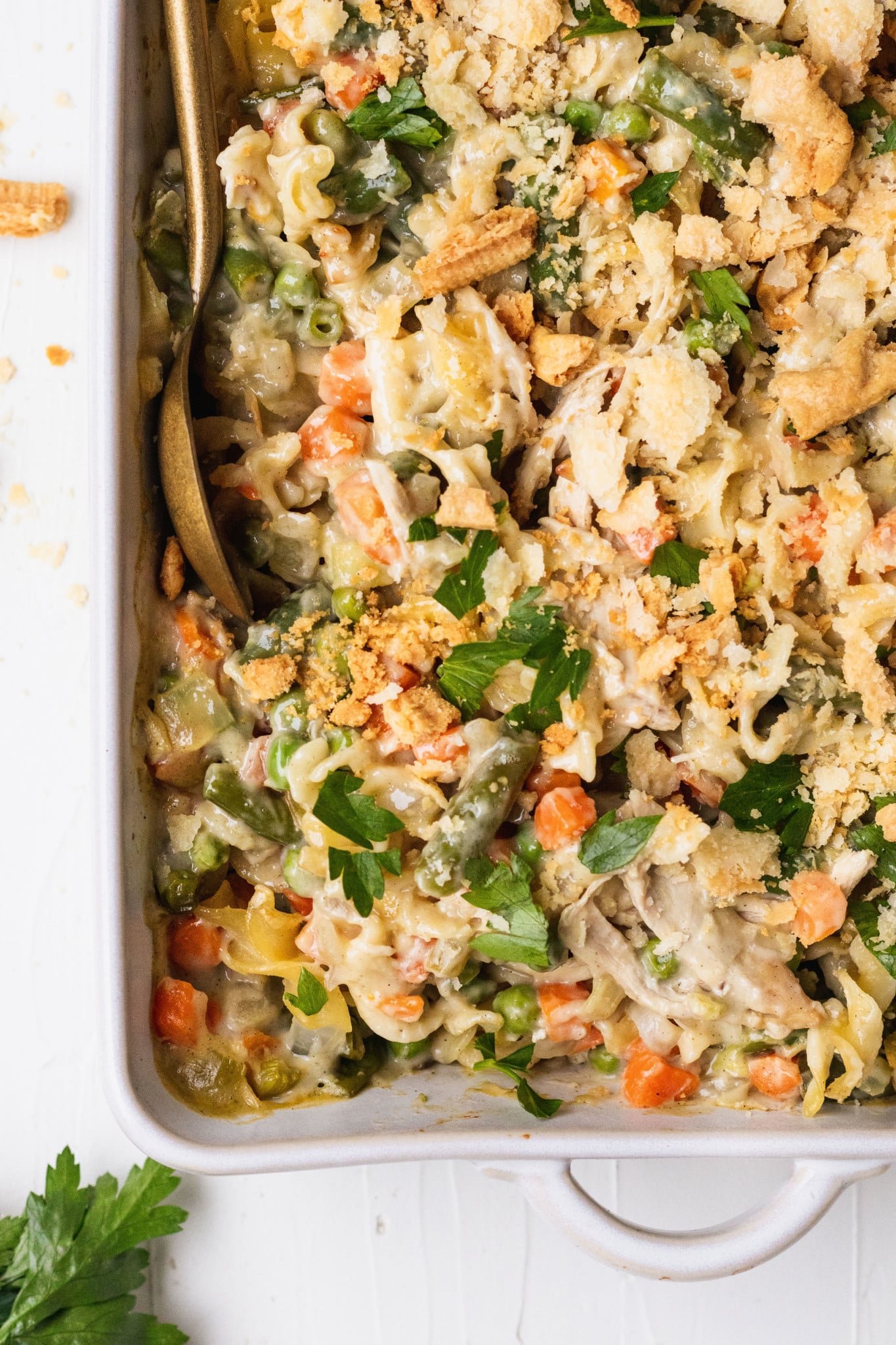 an up close image of a casserole loaded with egg noodles, carrots, green beans and topped with pie crust and parsley