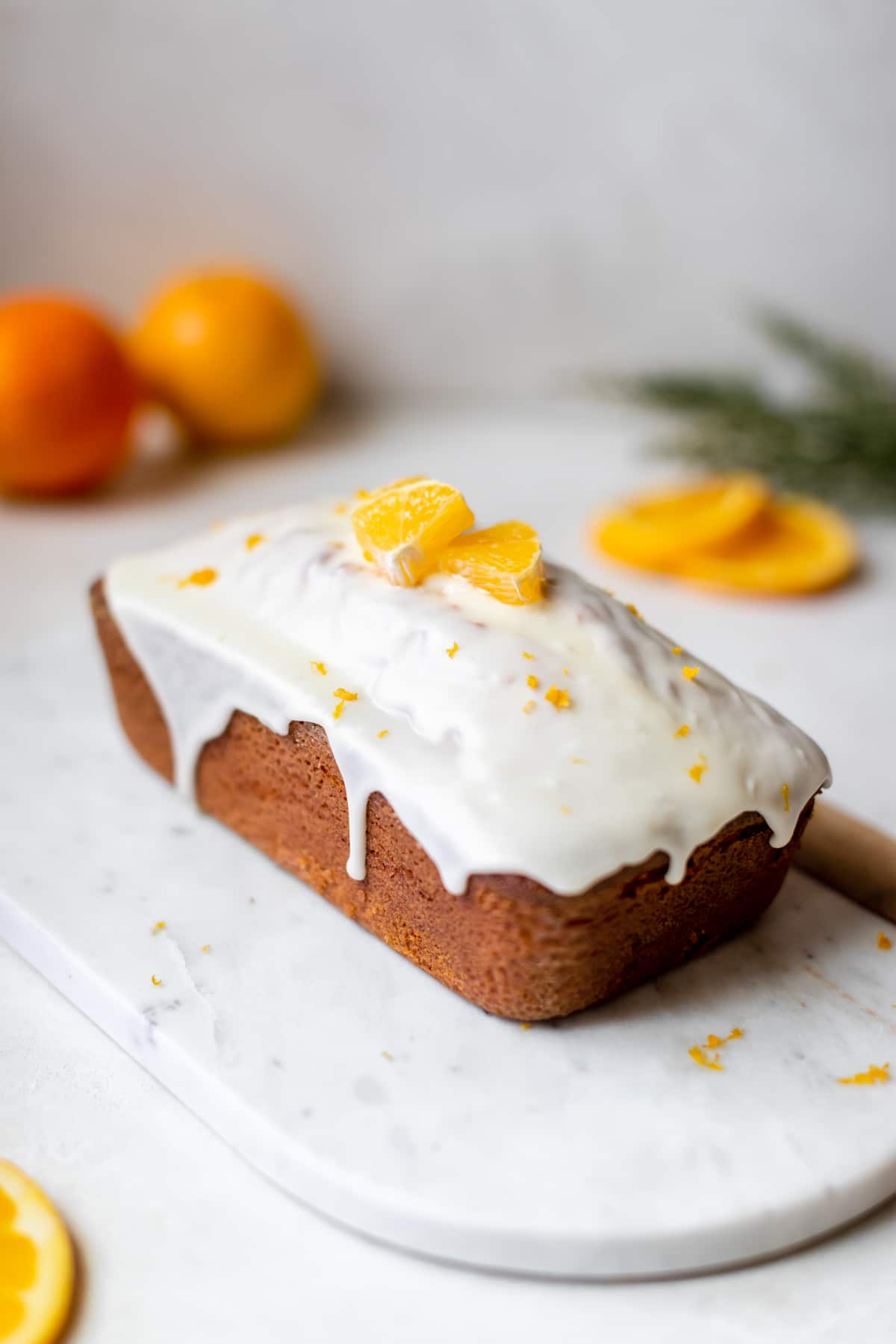 freshly baked pound cake with a glaze poured on top garnished with orange slices