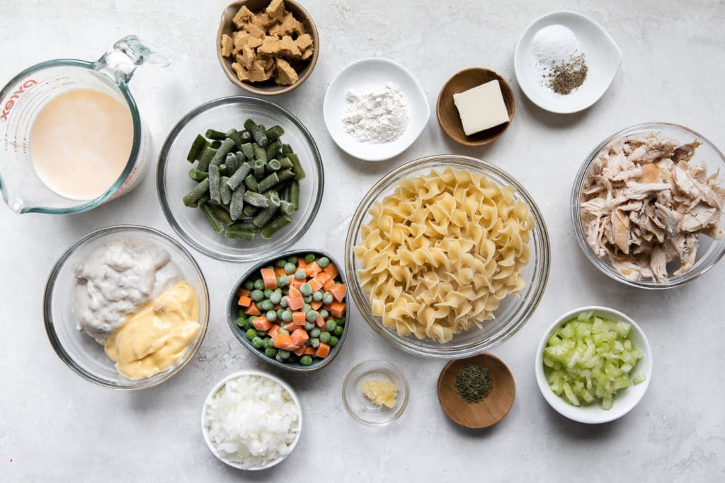 Multiple bowls of different sizes containing vegetables, onions, noodles, butter, and chicken