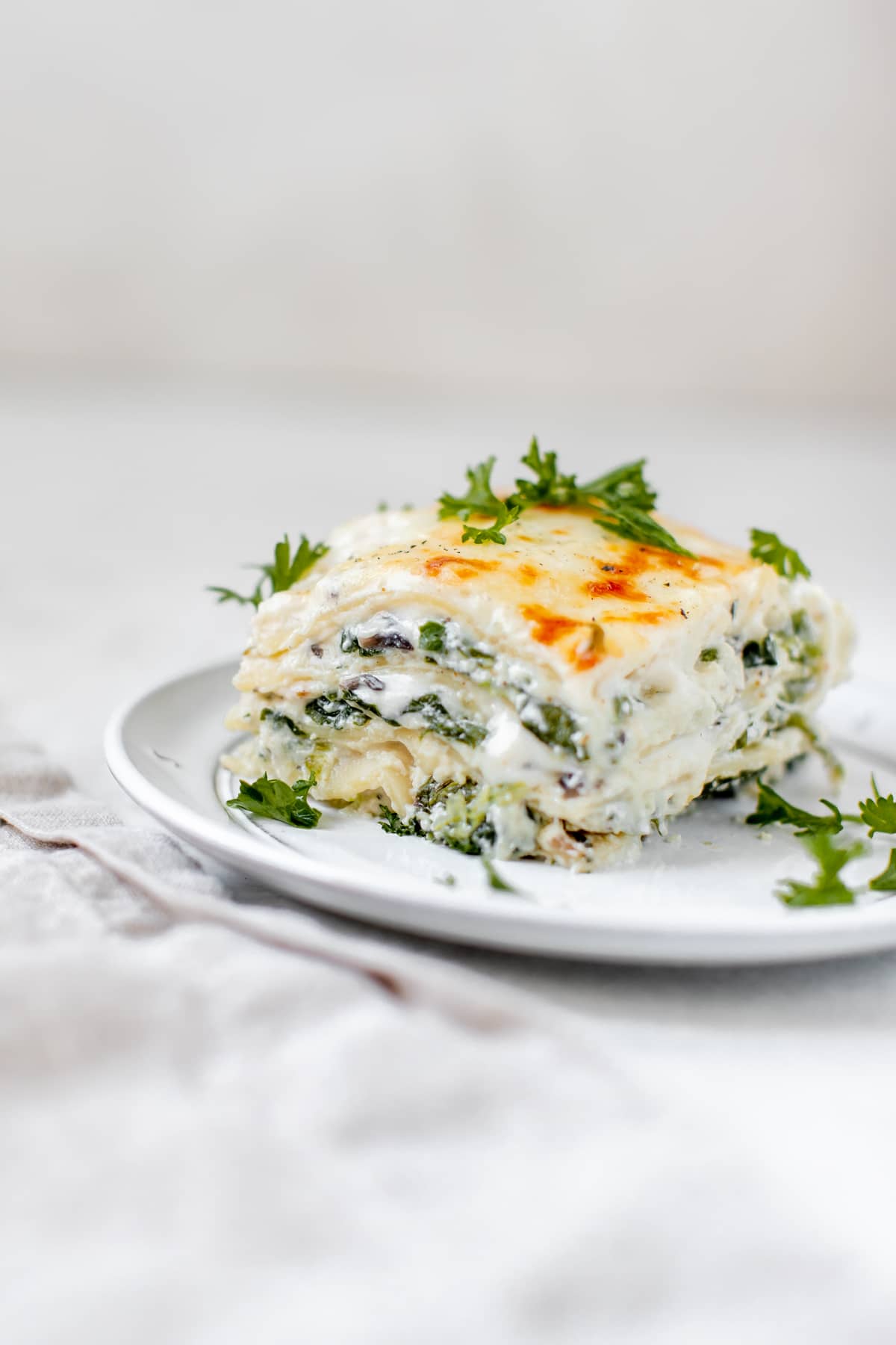 lasagna on a white plate topped with parsley