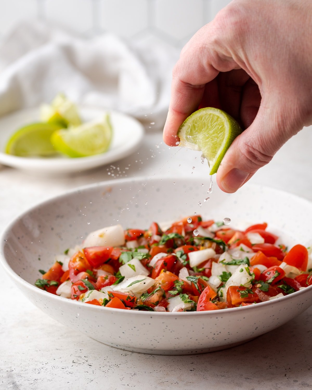lime juice being squeezed on pico de gallo