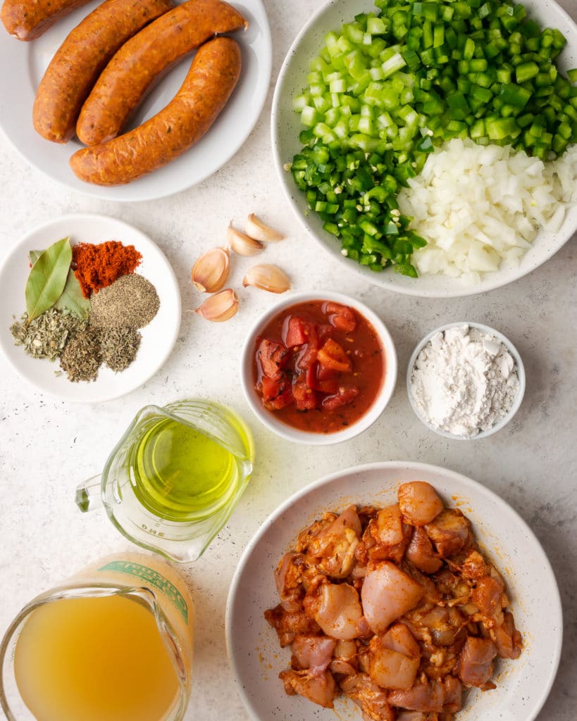 Ingredients to make gumbo in small white bowls. 