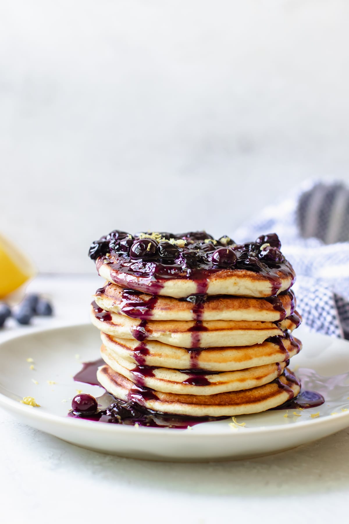 pancakes on a plate topped with blueberries and lemon zest