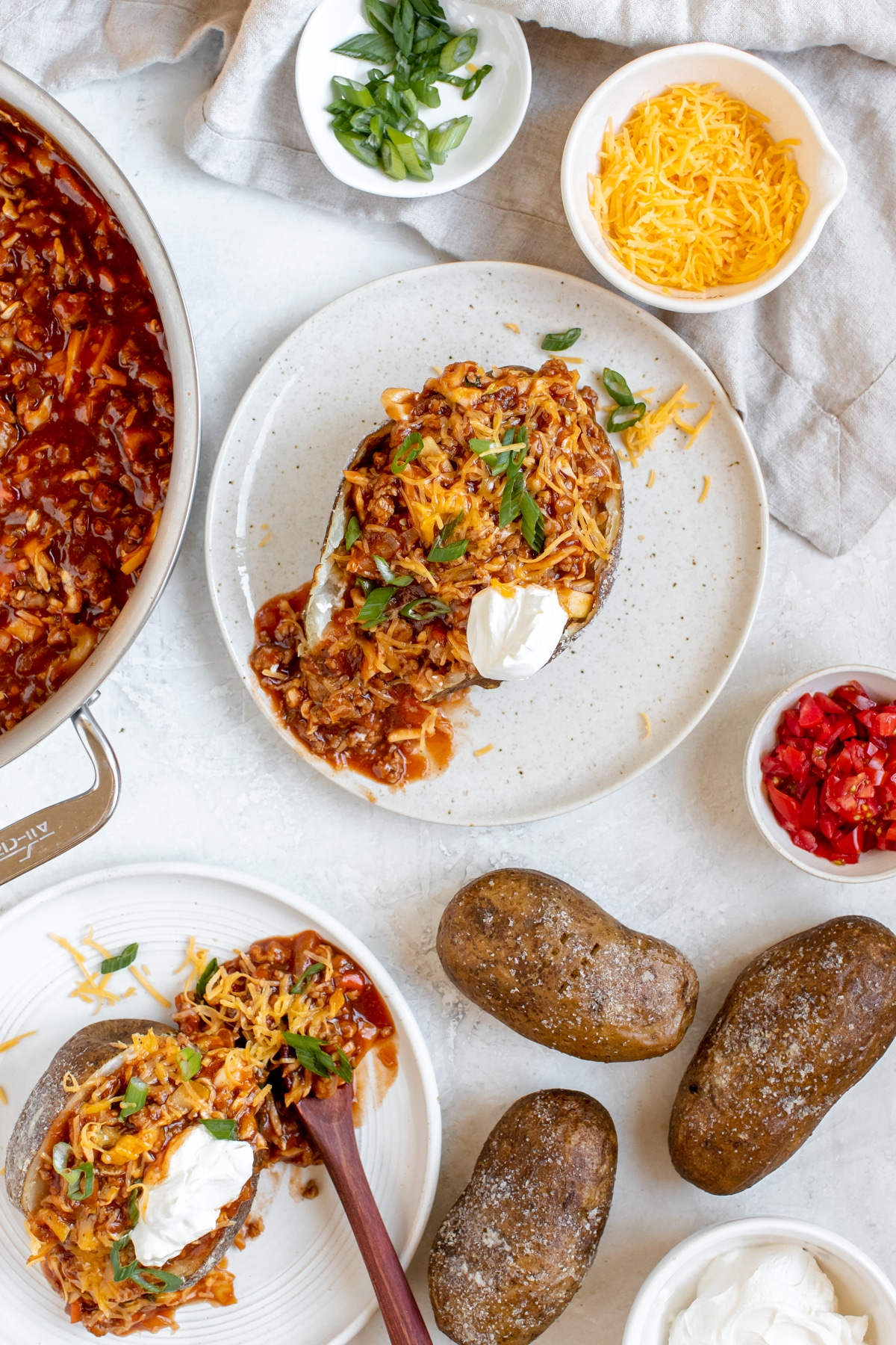 a baked potato stuffed with a ground turkey meat sauce and topped with cheese, green onions and sour cream